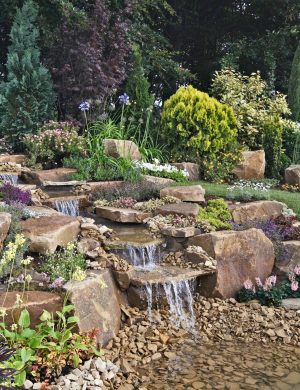 An,Attractive,Rock,Garden,With,Waterfall,Into,A,Water,Featured